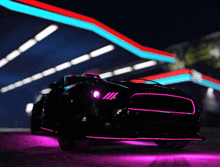 a black car with purple lights is parked in front of a gas station at night