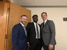 three men in suits and ties are posing for a photo