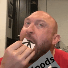 a bald man is holding a piece of paper in his mouth with the word pods on it