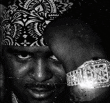 a black and white photo of a man wearing a bandana and a watch that says ryne