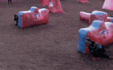 a man is playing paintball in a field with a red and blue bunker with the number 2 on it