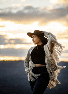 a woman wearing a hat and a fringed cardigan