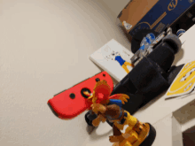 a red nintendo switch is sitting on a table next to a toy