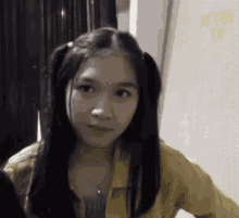 a girl with pigtails and a yellow jacket is standing in front of a wall that says jkt48 tv