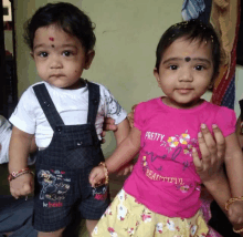 a girl wearing a pink shirt that says pretty and beautiful stands next to a baby