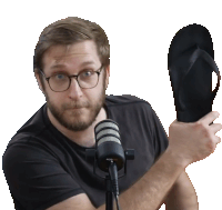 a man holds up a flip flop in front of a microphone