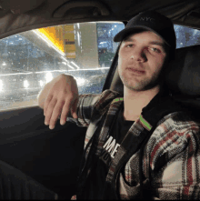 a man wearing a nyc hat is sitting in the driver 's seat of a car