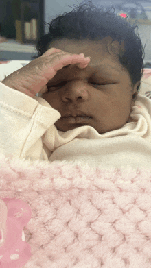 a baby laying on a pink blanket with her hand on her face