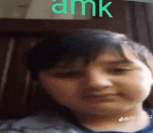 a close up of a child 's face with the word amk written on the wall behind him .