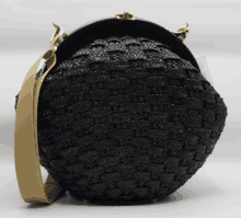 a black purse with a tan strap and a gold clasp