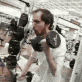 a man is lifting a dumbbell in a gym with a white shirt on