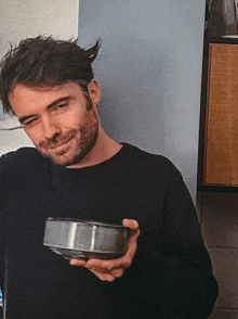 a man in a black shirt is holding a bowl