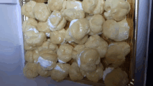 a tray of cream puffs with white frosting