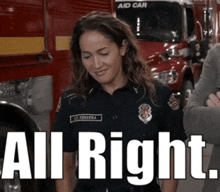 a woman in a firefighter uniform is standing in front of a fire truck with the words all right written on it