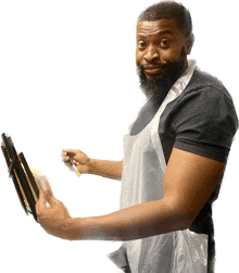 a man with a beard wearing a plastic apron is holding a tablet