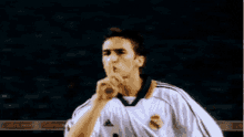 a man wearing a white adidas jersey holds his finger to his mouth