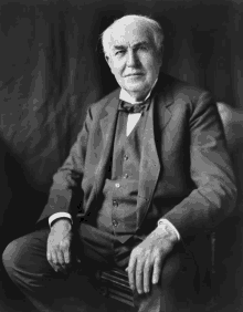 a man in a suit and bow tie sits on a chair