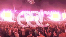 a crowd of people at a concert with a large edc logo in the foreground