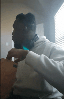 a man wearing headphones is sitting in front of a window with blinds on