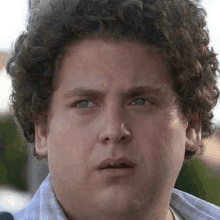 a young man with curly hair is making a funny face .