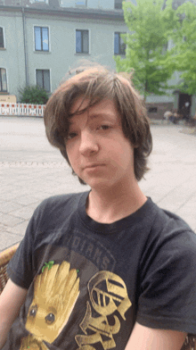 a boy wearing a t-shirt that says guardians sits in a chair