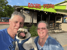 a man and woman holding a pug in front of adobe verde restaurant