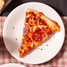 a slice of pepperoni pizza sits on a white plate