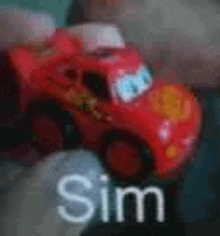 a person is holding a toy lightning mcqueen car in their hands .