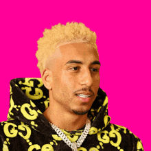 a man with blonde hair is wearing a black and yellow gucci sweatshirt