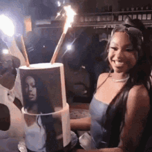 a woman in a blue dress is holding a birthday cake with a picture of a woman on it .