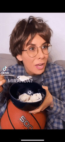 a woman wearing glasses is holding a bowl of ice cream and a basketball with the number 500 on it