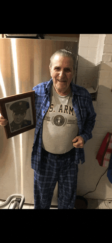 a man wearing a u.s. army shirt holds a framed picture of himself