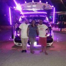 three people pose in front of a bus with the number 911 on the front