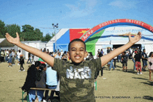 a boy wearing a star wars shirt is standing in front of a tent