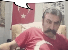 a man with a mustache is wearing a red shirt with a white star and crescent moon on it