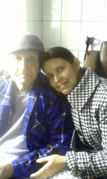 a woman in a plaid jacket sits next to an older man in a blue shirt