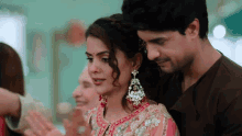 a man and a woman are standing next to each other and the woman is wearing earrings