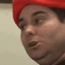 a close up of a person wearing a red hat and making a funny face .