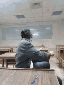 a person sitting at a desk with a pen in front of a whiteboard that says ' clock ' on it