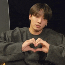 a man is making a heart shape with his hands