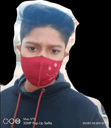 a young man wearing a red face mask is taking a selfie with a vivo v15