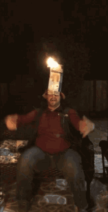 a man is sitting in a chair with a box on his head that has a flame on it