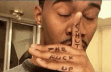 a man has the words shut the fuck up written on his finger