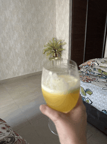 a person is holding a glass of beer in a bedroom