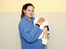 a woman is holding a newborn baby wrapped in a blanket .