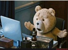 a teddy bear is sitting at a desk with a laptop