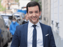 a man wearing a blue suit and tie smiles for the camera