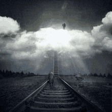 a black and white photo of a man walking down train tracks towards a sign that says heaven