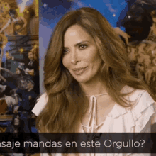 a woman with long brown hair is smiling in front of a sign that says " saje manda en este orgullo "