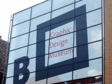 a graphic design museum sign is reflected in the windows of a building